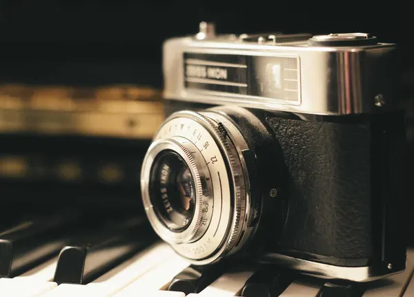 A vintage camera and lens resting on a dark surface